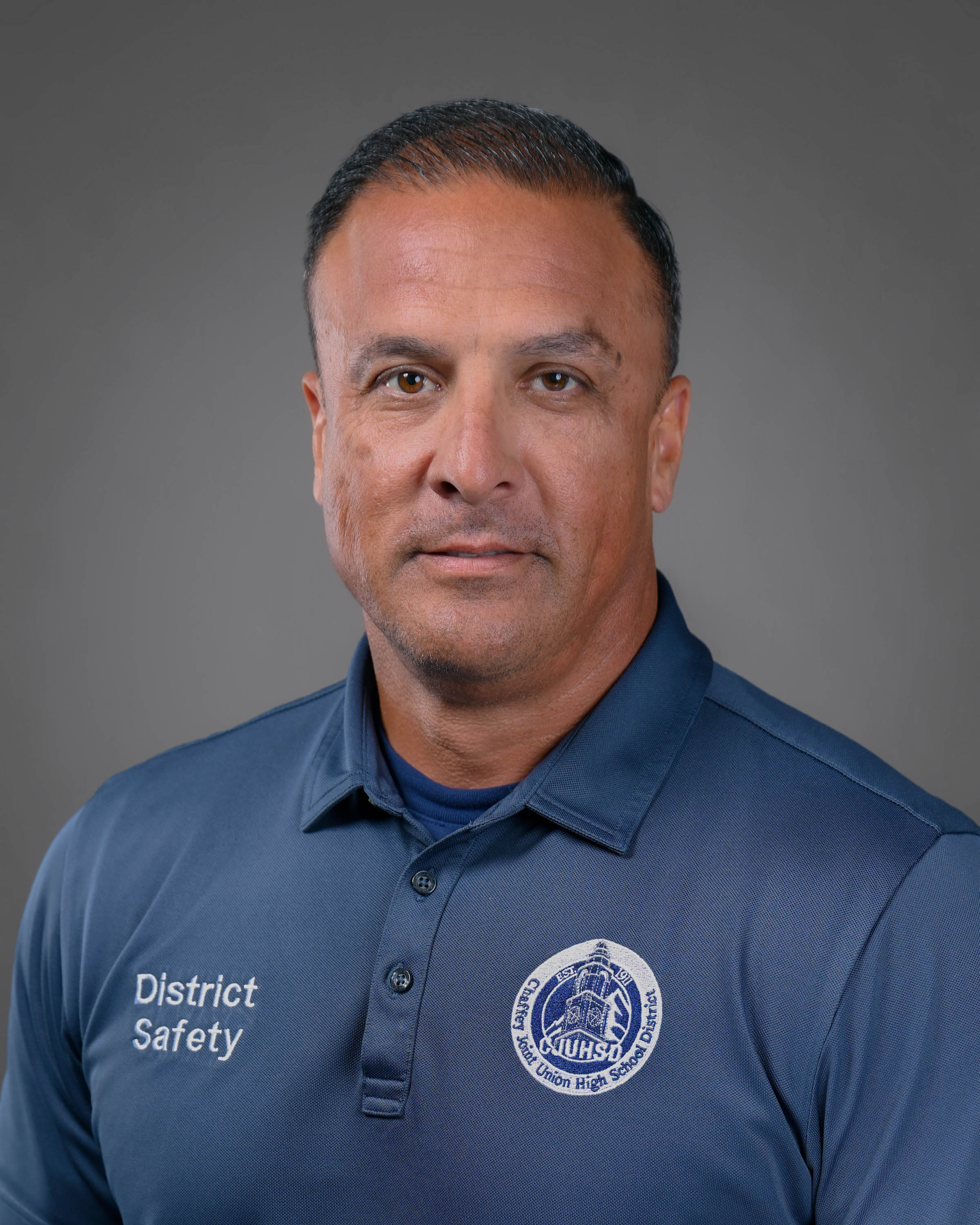 Clean-shaven man with dark brown hair and a blue polo shirt.